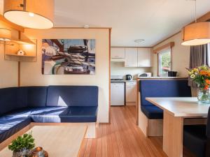 ein Wohnzimmer mit einem blauen Sofa und einer Küche in der Unterkunft Nice chalet in a holiday park with swimming pool, on the Leukermeer in Well