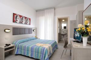 a bedroom with a bed and a desk and a television at Hotel Tiberius in Rimini