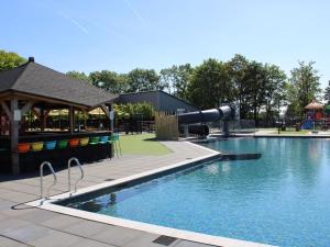 uma piscina com escorrega e um parque infantil em Nice chalet with hot tub in a holiday park directly on a recreational lake em Lathum