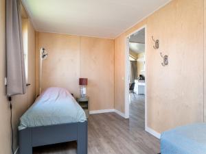 a small bedroom with a bed and a hallway at Disabled house on the water, on a holiday park in Friesland in Akkrum