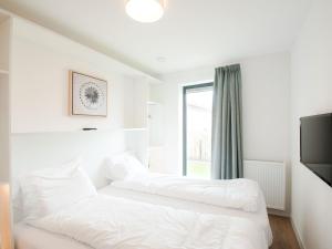 Duas camas num quarto branco com uma janela em Modern design lodge with combi microwave, in national park em Tholen