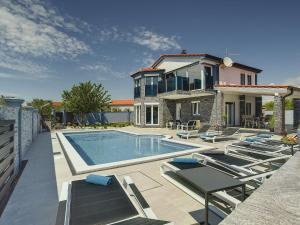 uma casa com piscina e espreguiçadeiras em Modern villa in Fa ana with private pool em Valbandon