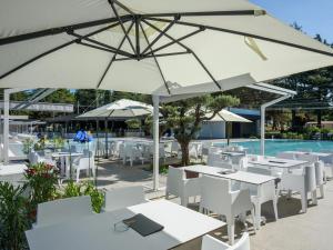 ein Restaurant mit weißen Tischen und Sonnenschirmen neben einem Pool in der Unterkunft Modern chalet with 2 bathrooms and a veranda in Vrsar