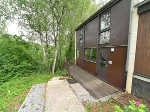 une maison avec une rampe en bois menant à une terrasse couverte dans l'établissement Semi-detached bungalow for 6 people next to the Lac de Vallée de Rabais, à Virton