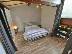 1 dormitorio con 1 cama y suelo de madera en Semi-detached bungalow for 6 people next to the Lac de Vallée de Rabais, en Virton