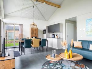 een woonkamer en een keuken met een blauwe bank en tafels bij Beautiful bungalow with an unobstructed view, on a holiday park in Friesland in Akkrum