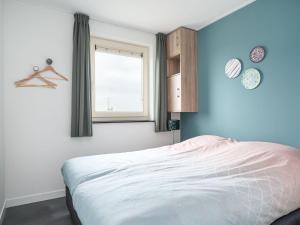 een slaapkamer met een bed met een blauwe muur bij Beautiful bungalow with an unobstructed view, on a holiday park in Friesland in Akkrum