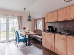 a kitchen with wooden cabinets and a table with blue chairs at Covered Terrace Chalet at Leukermeer in Well