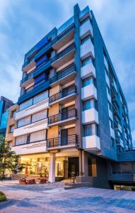 un edificio alto azul con bancos delante en Hotel Viaggio Nueve Trez, en Bogotá