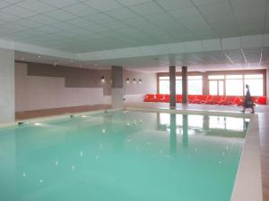 a swimming pool with blue water in a room with red chairs at Modern apartment near the ski lift in an authentic village in Sainte-Foy-Tarentaise