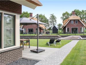 eine Terrasse mit einem Sonnenschirm, Stühlen und einem Tisch in der Unterkunft Atmospheric villa with nice garden, in a holiday park at the water in Friesland in Idskenhuizen