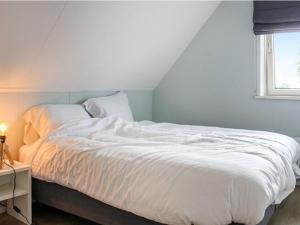 ein weißes Bett in einem Zimmer mit Fenster in der Unterkunft Atmospheric villa with nice garden, in a holiday park at the water in Friesland in Idskenhuizen