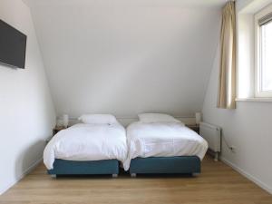 2 aparte bedden in een kamer met een raam bij Atmospheric villa on the water, at a holiday park in Friesland in Idskenhuizen