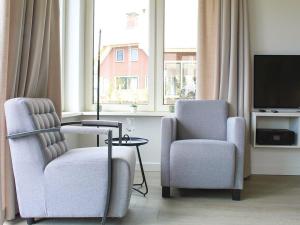 - un salon avec deux chaises et une télévision dans l'établissement Wellness villa with sauna, at a holiday park on the water in Friesland, à Idskenhuizen