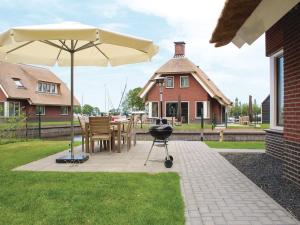 - un barbecue et un parasol sur la terrasse dans l'établissement Wellness villa with sauna, at a holiday park on the water in Friesland, à Idskenhuizen