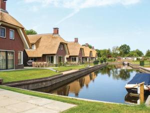 een rij huizen naast een kanaal met een boot bij Atmospheric villa on the water, at a holiday park in Friesland in Idskenhuizen