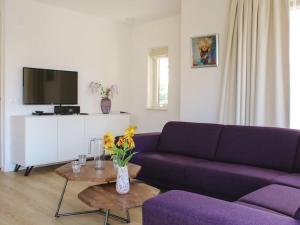 een woonkamer met een paarse bank en een tv bij Atmospheric villa on the water, at a holiday park in Friesland in Idskenhuizen