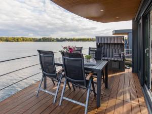 una terraza de madera con mesa y sillas en un barco en Houseboat with a view over the Leukermeer, on the edge of a holiday park, en Well
