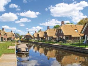 a boat in a canal in front of houses at Villa in Friesland with Sauna & Bubble Bath in Idskenhuizen