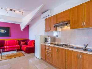uma cozinha com armários de madeira e um sofá vermelho em Peaceful Apartment in Pula with Swimming Pool em Valtura