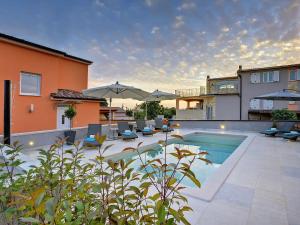 a swimming pool with chairs and umbrellas next to a house at Modern Villa with Pool and Parasol in Pula in Pula