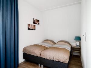 een bed in een slaapkamer met een blauw gordijn bij Spacious holiday home with outdoor spa, on a holiday park in Friesland in Akkrum
