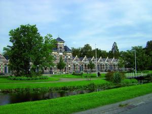 een groot gebouw met een vijver ervoor bij Spacious holiday home with outdoor spa, on a holiday park in Friesland in Akkrum