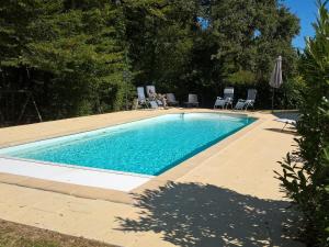 una piscina en un patio con sillas y sombrilla en Detached villa with large garden near beautiful golf course, en Vasles