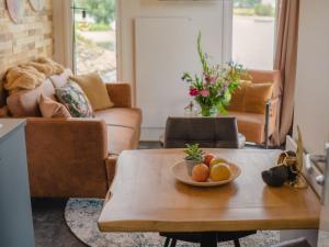 una sala de estar con una mesa con naranjas. en Cozy tiny house on the water, located in a holiday park in the Betuwe en Maurik