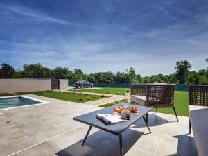 eine Terrasse mit einem Tisch, Stühlen und einem Pool in der Unterkunft Modern villa swimming pool , outdoor kitchen and fenced garden in Pula