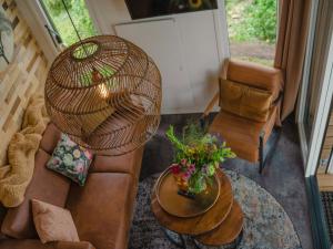 a living room with a wicker fan and a table at Cozy tiny house on the water, located in a holiday park in the Betuwe in Maurik