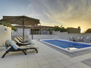 um pátio com cadeiras, um guarda-sol e uma piscina em Detached house with private pool, 15 minutes drive from the coast em Vodnjan