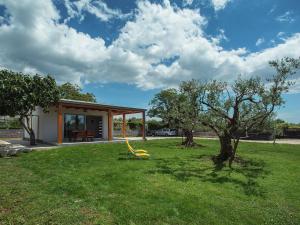 a house with a green yard with a tree at Modern, detached holiday home with enclosed garden, near the centre and the beach in Fažana