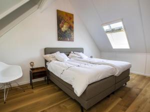 een slaapkamer met een groot bed met witte lakens bij Modern villa with spacious garden, on a holiday park in Friesland in Sint Nicolaasga
