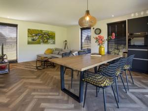 a kitchen and living room with a wooden table and chairs at Modern villa with spacious garden, on a holiday park in Friesland in Sint Nicolaasga