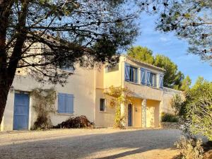 duży biały dom z niebieskimi oknami i podjazdem w obiekcie Modern villa with private pool w mieście Pouzols-Minervois