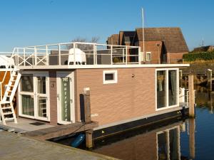 a house boat is docked at a dock at Lush houseboat with roof terrace in Lemmer in Lemmer