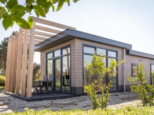 una casa pequeña con techo inclinado y ventanas en Modern chalet with dishwasher on Texel, en De Cocksdorp