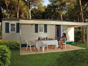 a woman sitting at a table under a shed at Detached chalet with AC, in a natural park on the coast in Baia Domizia
