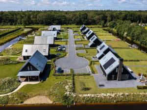 una vista aérea de una granja con una fila de edificios en Beautiful villa on the water, on a holiday park in Friesland, en Sint Nicolaasga