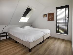 a bedroom with a bed with white sheets and a window at Beautiful villa on the water in Friesland in Sint Nicolaasga