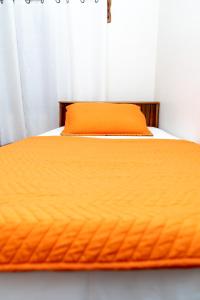 a bed with an orange comforter on it at Francis Nook Bourg Mulatresse Room in San Juan