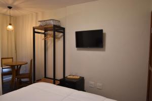 a bedroom with a bed and a tv on the wall at Pousada Villa Manso in Conceição da Ibitipoca