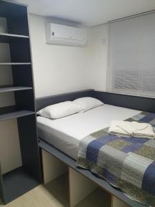 a small bedroom with a bed and a book shelf at Apartamento 509 Gravataí in Gravataí