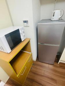a microwave sitting on a counter next to a refrigerator at SUNPIA WOMBLE GATE l 大滝町 in Kusugaurachō