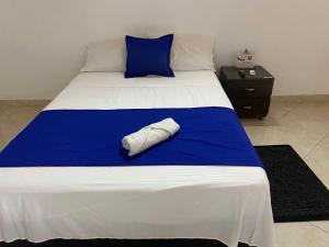 een bed met een blauwe en witte deken en een kussen bij Casa Hotel La Palmera Apartadó in Apartadó