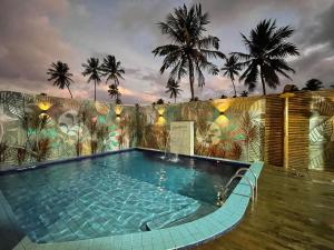 a swimming pool in the middle of a building with palm trees at Chalé Palhano Beach in São Miguel dos Milagres