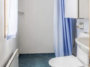 a bathroom with a toilet and a blue shower curtain at Holiday home JÄRPEN II in Järpen