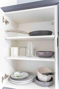 a white shelf with plates and bowls on it at Stylish cosy studio in Selly Oak in Birmingham