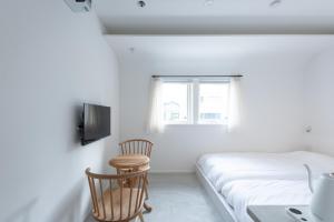 een slaapkamer met een bed, een tafel en een raam bij NODE SAIGAWA in Kanazawa